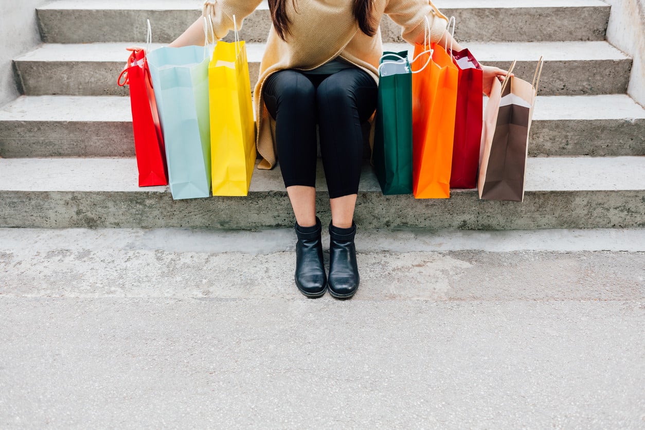 Mujer sujetando bolsas de compra en una escalera, después de seguir las recomendaciones y consejos para el Black Friday 2024