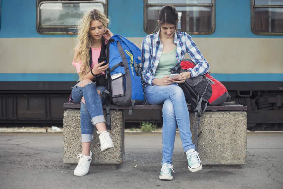 Chicas mochileras en una estación de tren, esperando para viajar gratis con Interrail Pass