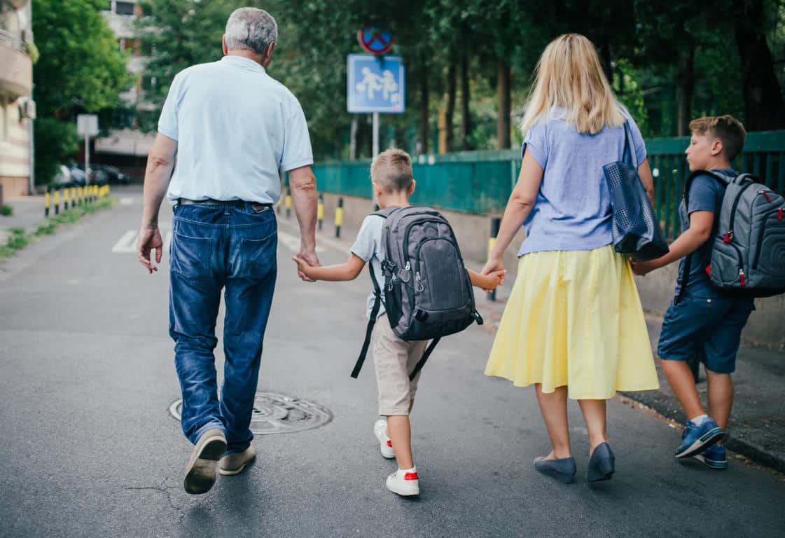 Familia de madre, padre e hijo tomados de la mano caminando en septiembre