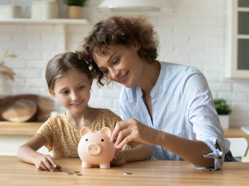 Madre e hija metiendo dinero en una hucha aprendiendo de ahorro