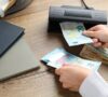 Persona intentando detectar billetes falsos con una máquina