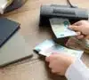Persona intentando detectar billetes falsos con una máquina