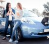 Chicas cargando un coche sostenible mientras hablan