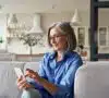 Mujer mayor mirando un teléfono móvil en su casa