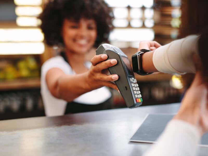 Mujer pagando en un establecimiento a través de pagos digitales como el smartwatch.