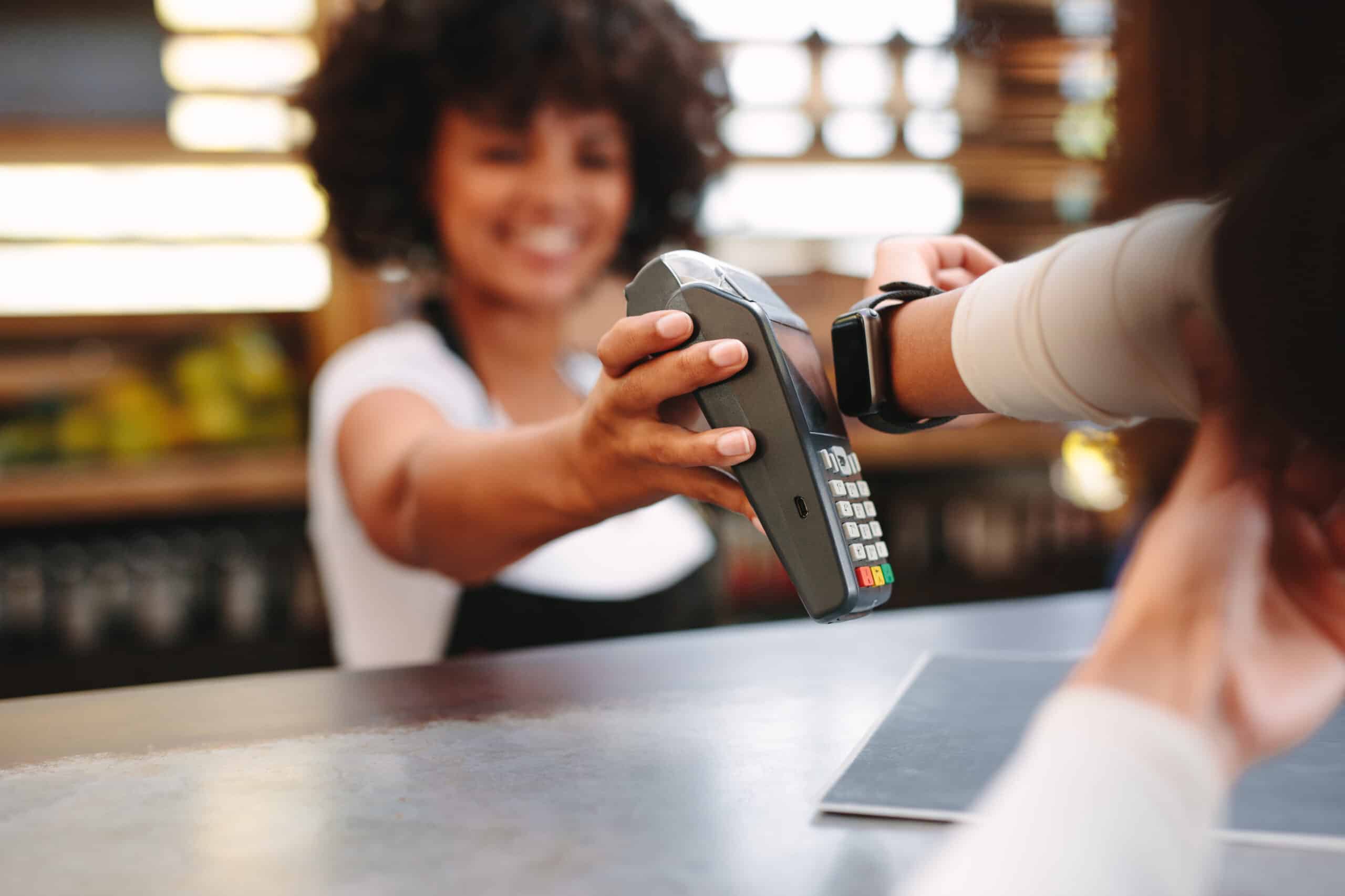 Mujer pagando en un establecimiento a través de pagos digitales como el smartwatch.
