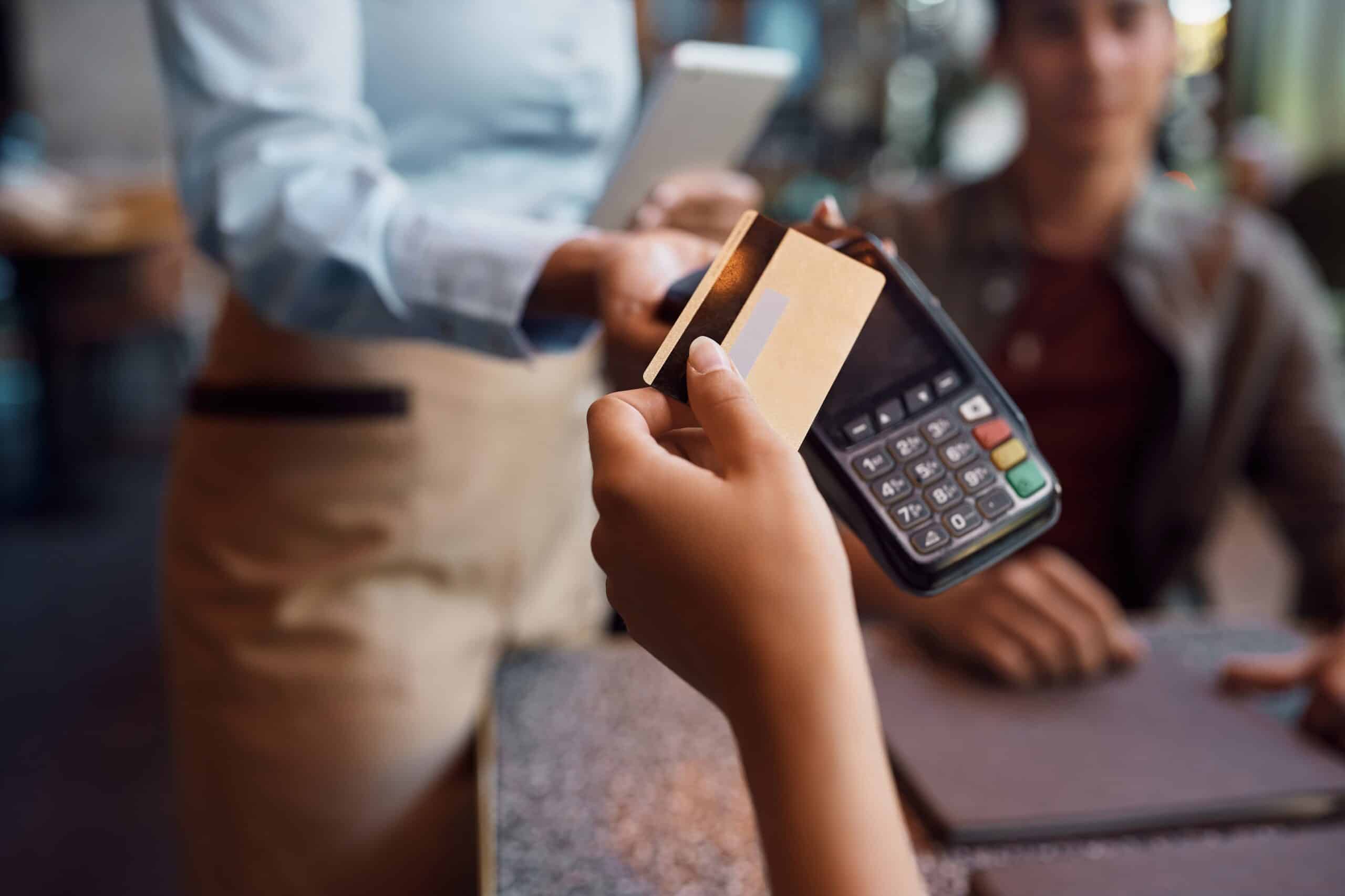 Mujer pagando con su tarjeta en un datáfono, preguntándose si el pago con tarjeta es obligatorio