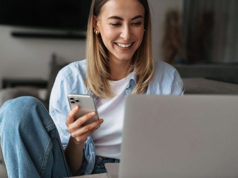Mujer con su móvil y ordenador descubriendo cómo abrir una cuenta online