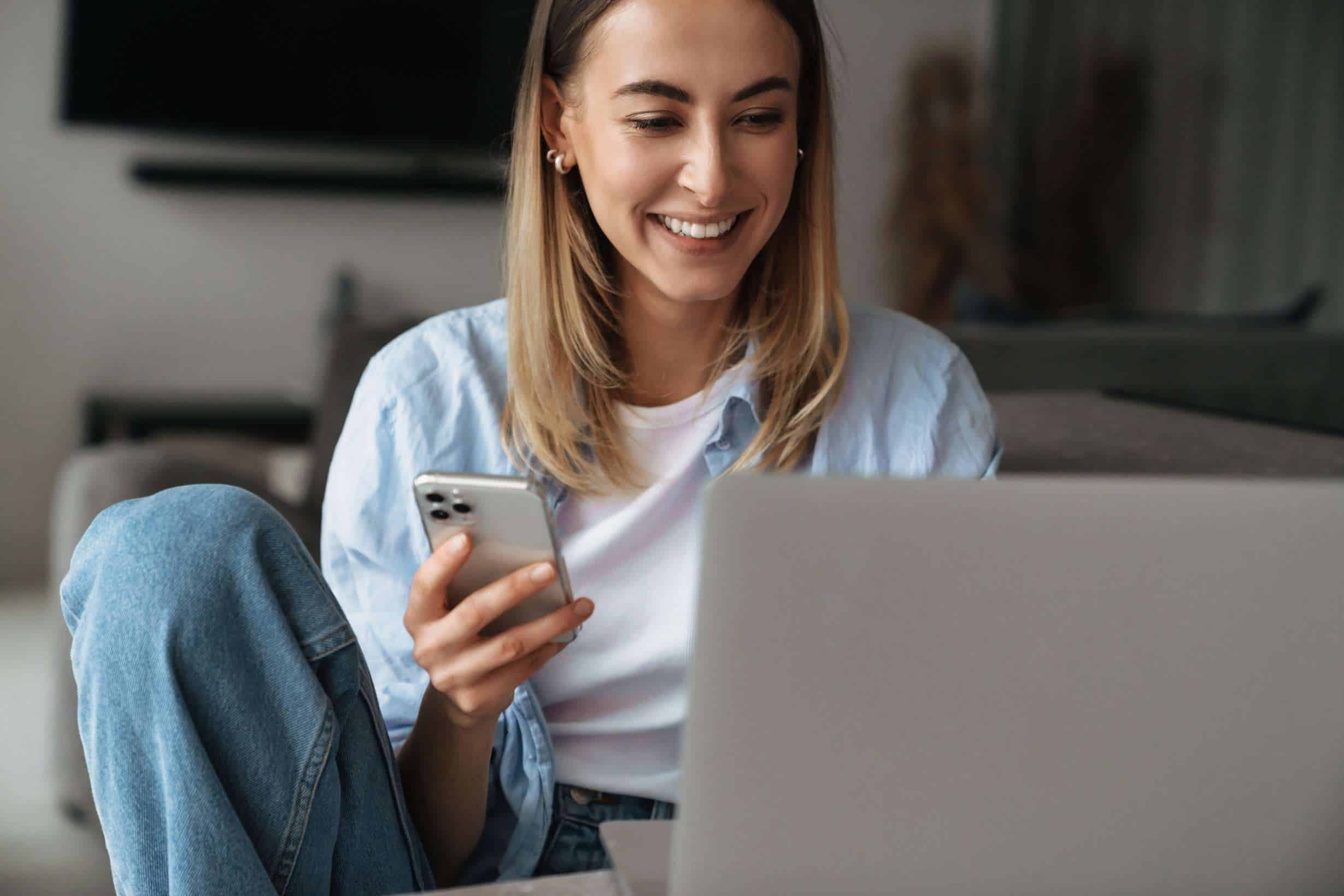 Mujer con su móvil y ordenador descubriendo cómo abrir una cuenta online bancaria