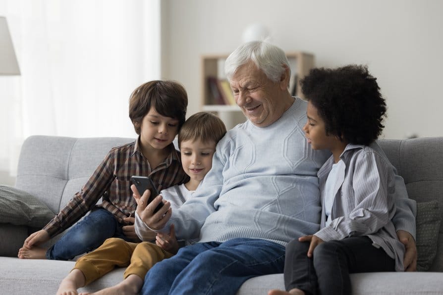 Abuelo y tres niños con un móvil descubriendo la brecha digital.