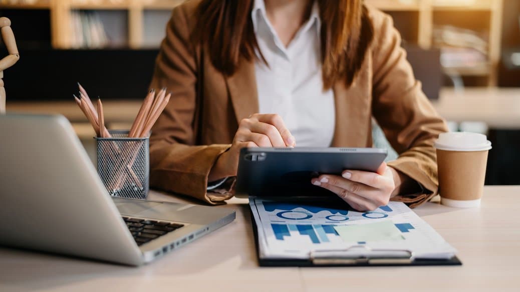 Mujer en un escritorio, mirando una tablet y descubriendo como organizar las finanzas del negocio