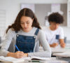 Chica estudiando en un salón de clases, pensando en un préstamo de estudios