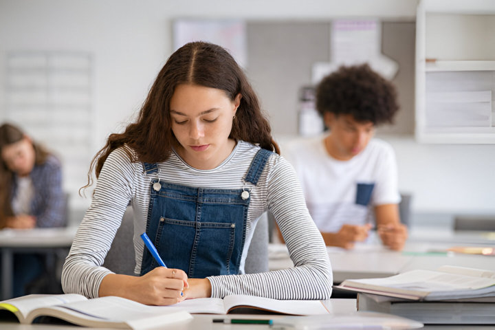 Chica estudiando en un salón de clases, pensando en un préstamo de estudios