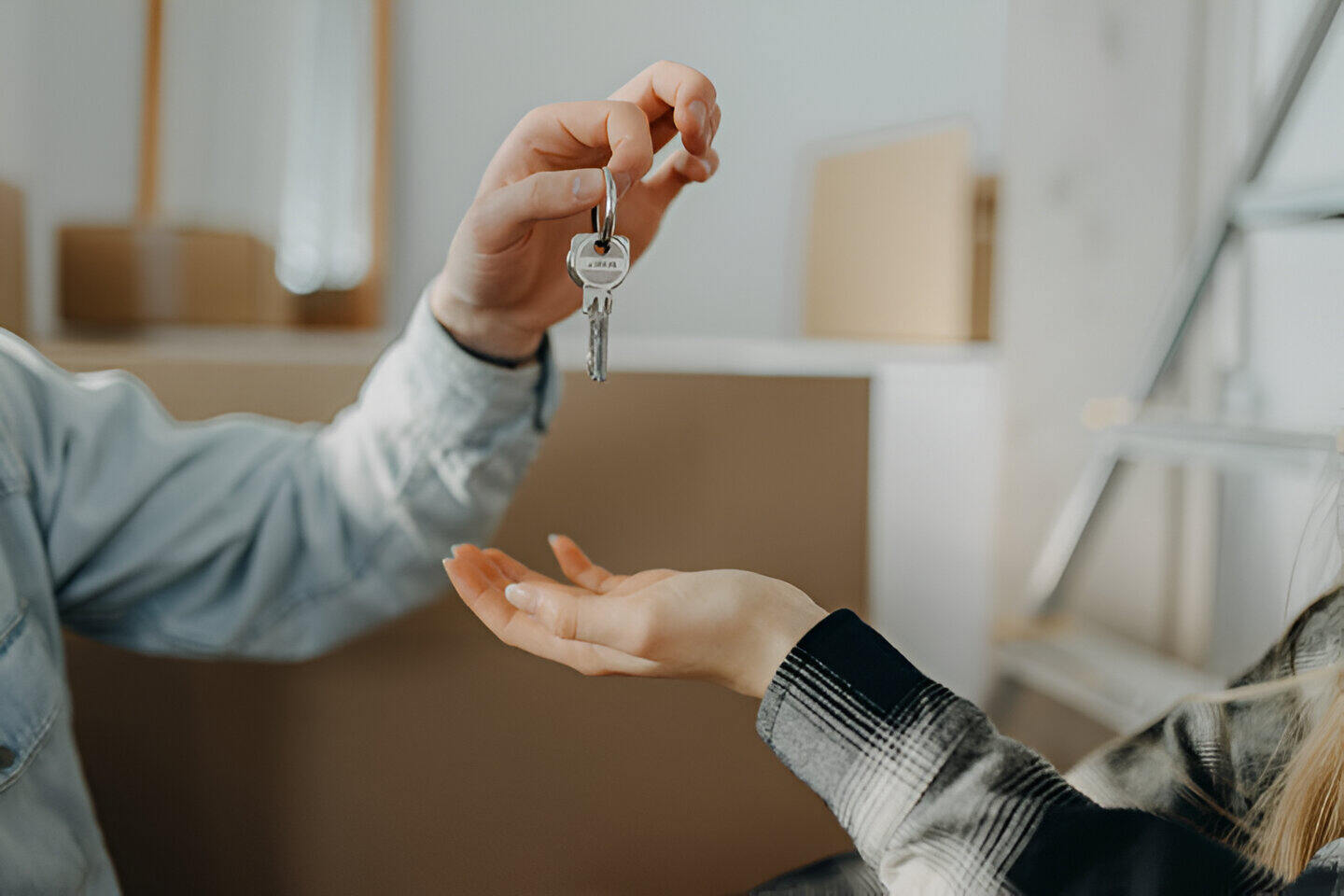 La mano de una persona entregando las llaves de su nuevo hogar a otra persona, gracias al convenio de Mi Primera Vivienda en Madrid