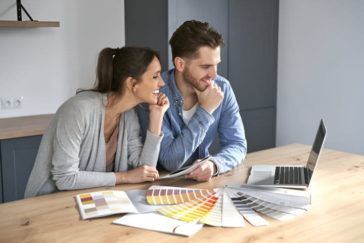 Pareja joven mirando el portátil mientras eligen su nueva vivienda, gracias a la hipoteca compartida