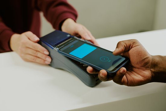 Mano de una persona pagando con su teléfono móvil en un TPV, gracias a su wallet digital