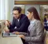 Mujer y hombre buscando en el portátil que es nis2 y cómo afecta a las empresas