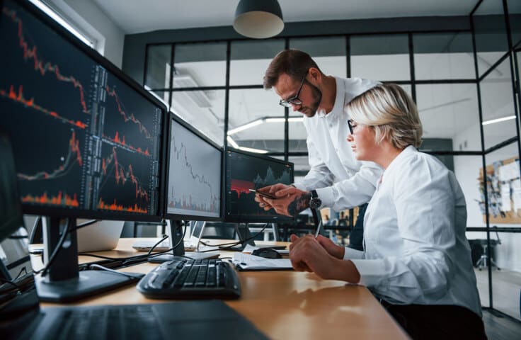 Inversionistas revisando gráficos de inversiones, descubriendo qué es una OPA