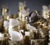 Figuras de cisnes blancos y un cisne negro representando la economía encima de unas monedas