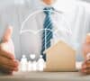 Manos de una persona protegiendo la figura de una casa y una familia, representando qué es una vivienda de protección oficial