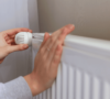 Manos de mujer consultando el calor que emite un radiador